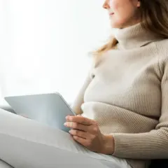 Kobieta w beżowym golfie korzysta z tabletu, szukając informacji o psychiatra online e-recepta.