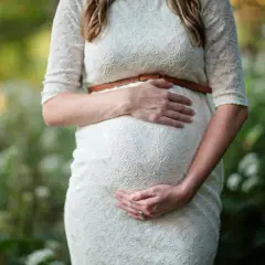 Kobieta w białej sukience delikatnie obejmuje ciążowy brzuch. Czy po owulacji można zajść w ciążę? To pytanie nurtuje wiele par.