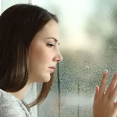 Smutna dziewczyna patrzy przez zaparowane okno. Czy to chandra?