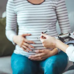 Lekarz bada ciężarną, trzymając termometr i USG. Ważne jest monitorowanie zdrowia w ciąży, aby wykluczyć np. cytomegalię.