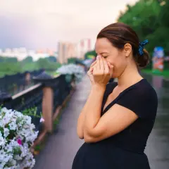Kobieta w ciąży kicha, szukając bezpiecznych leków na alergię.
