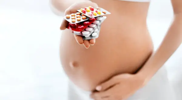 Ciężarna kobieta trzyma opakowania leków, szukając odpowiedzi na pytanie: co na alergie w ciąży.