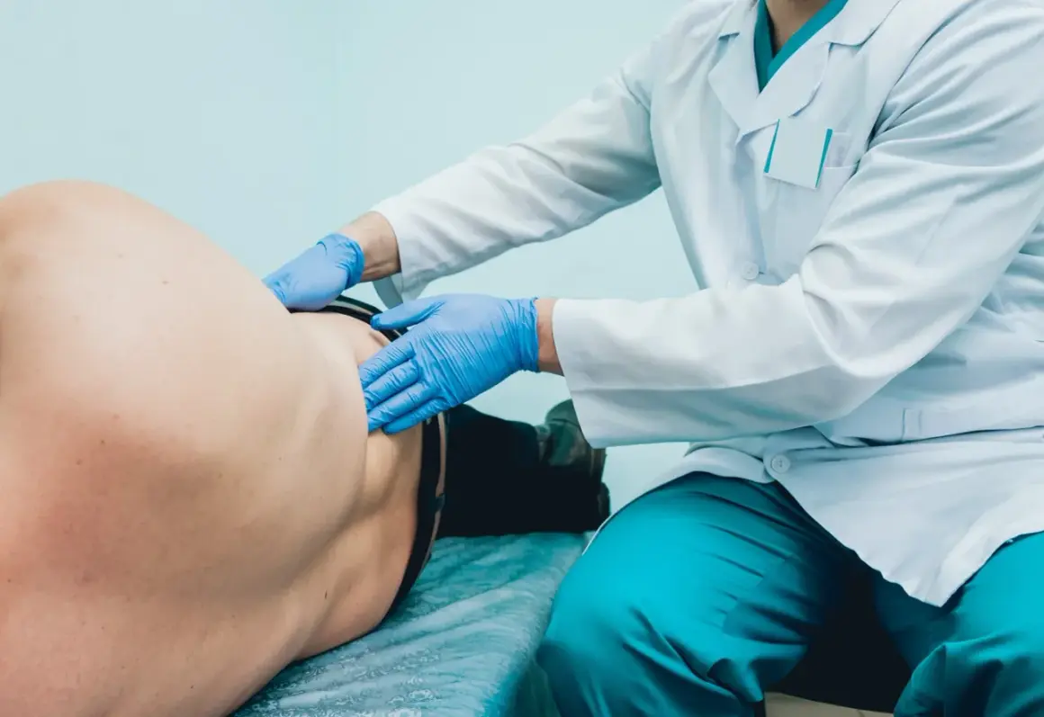 Lekarz w rękawiczkach bada pacjenta, pokazując, jak wygląda badanie urologiczne u mężczyzn.