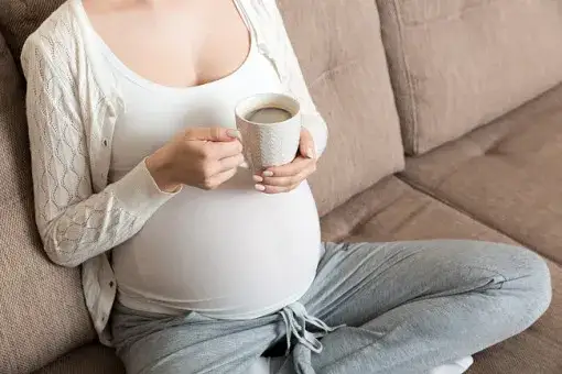 kobieta w ciąży pije kawę w kawiarni