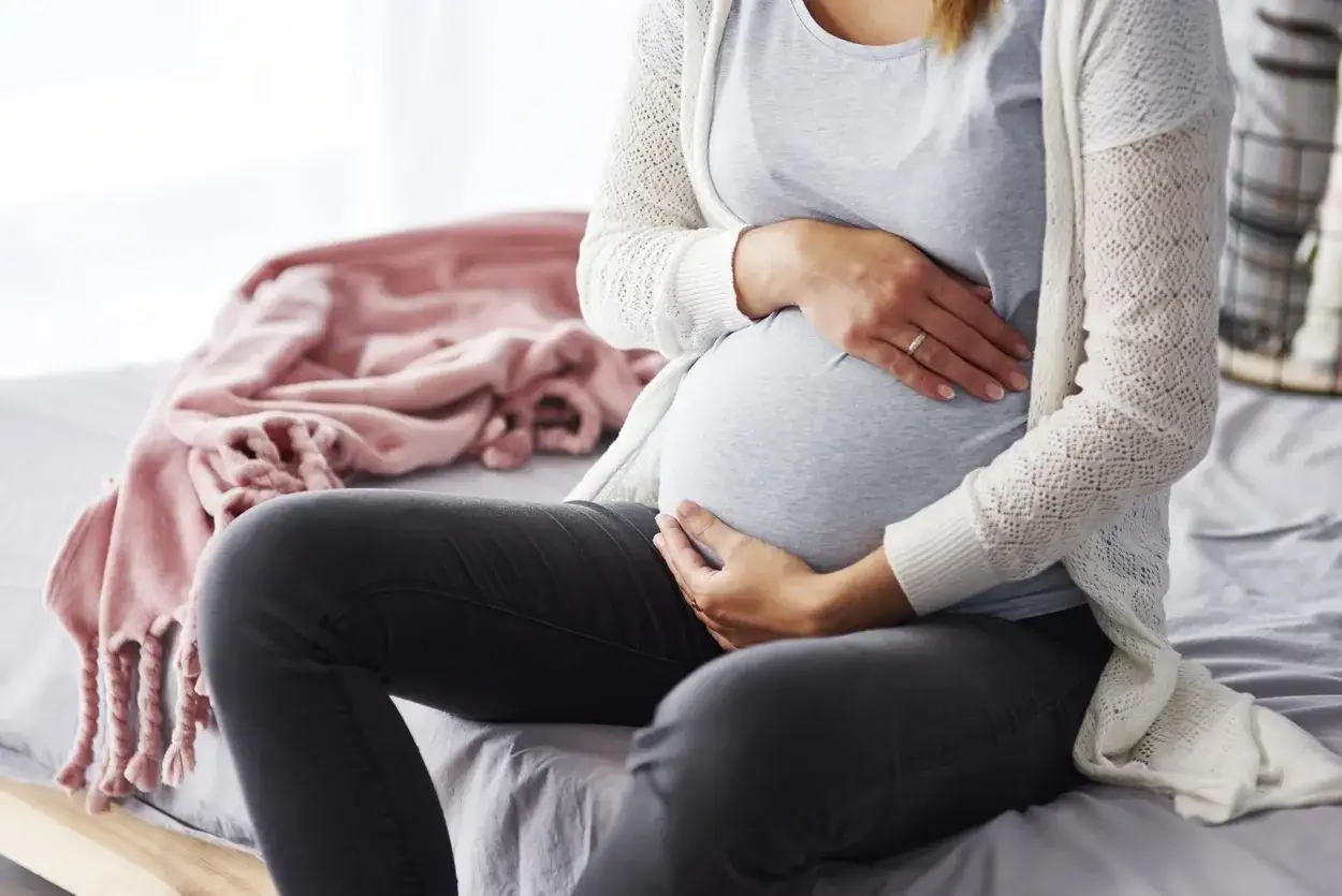 Kobieta w ciąży czytająca dokumenty ZUS, kobieta w ciąży rozmawiająca z urzędnikiem