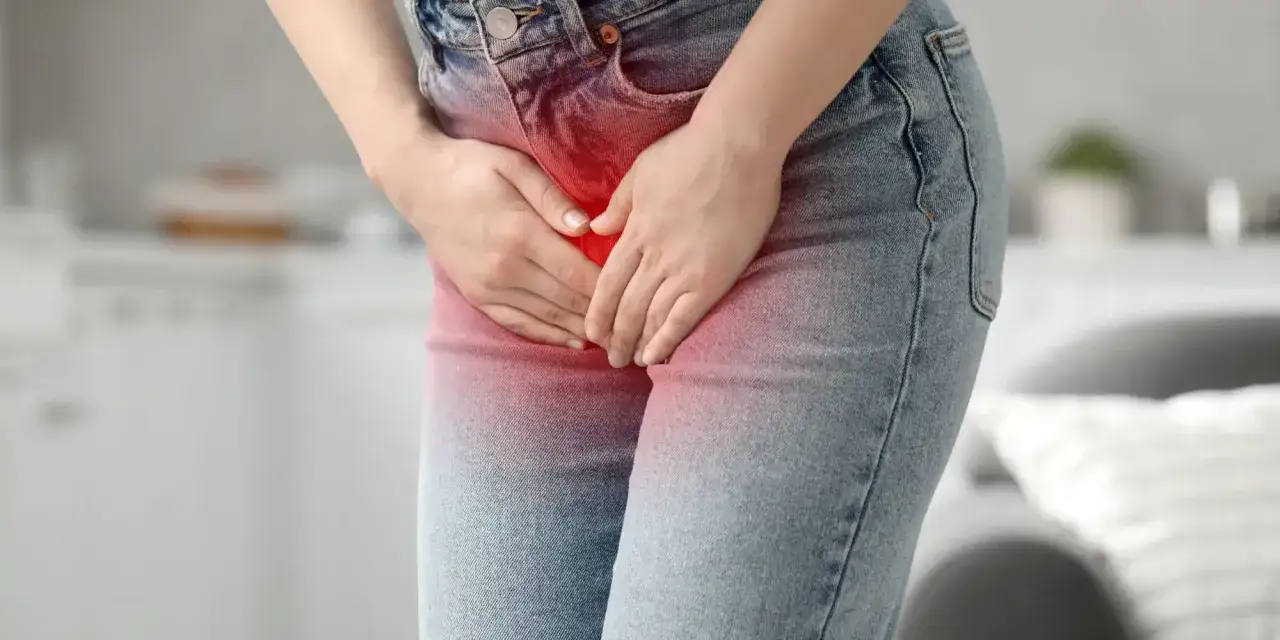 Kobieta trzyma ręce na podbrzuszu, gdzie widoczny jest czerwony obszar bólu, sugerujący zapalenie pęcherza. Może szukać ulgi, np. za pomocą Ibupromu.